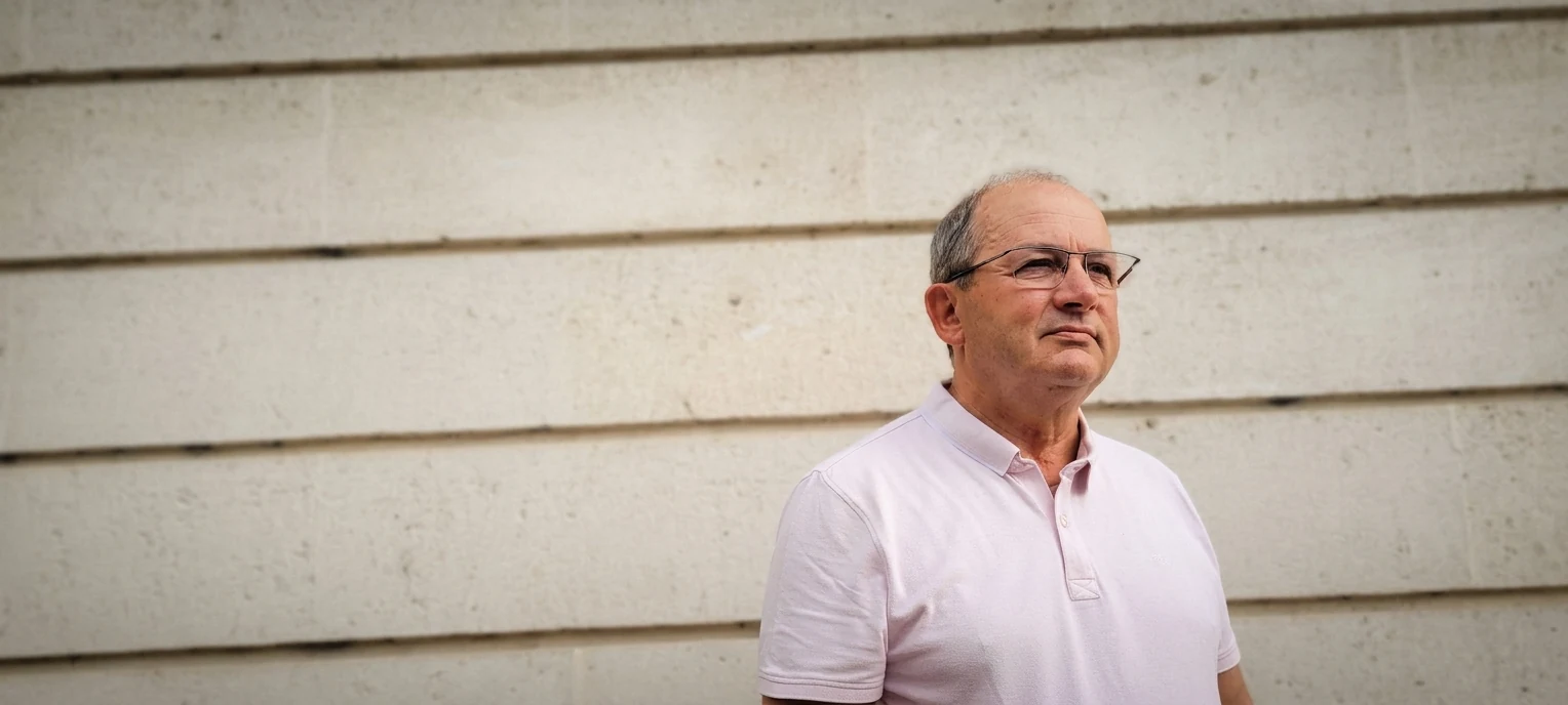 Etienne Chevé, en polo clair, devant un mur de béton